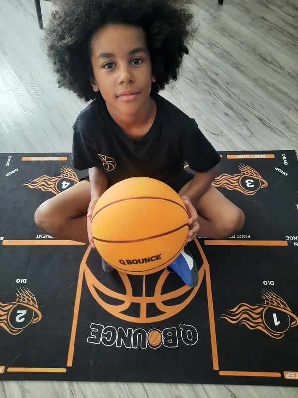 Young player sitting on the QBounce training mat with the QBounce ball