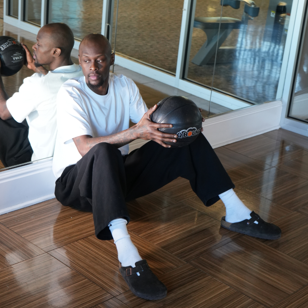 Taze Moore sitting with a QBounce Weighted Basketball