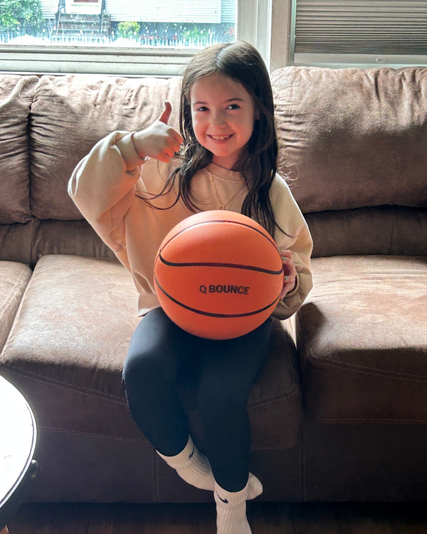 Girl on a sofa giving a thumbs up with the QBounce ball
