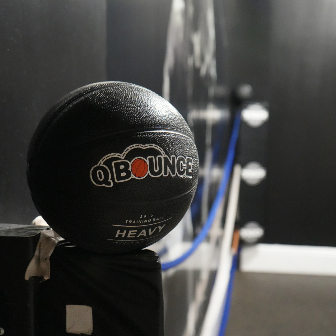 QBounce Weighted Basketball in black with textured surface for enhanced training, strength, and precision in a gym setting.