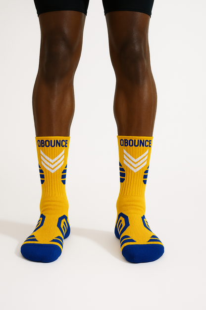 Close-up of legs wearing yellow and blue QBounce Grip Socks designed for enhanced agility and grip.